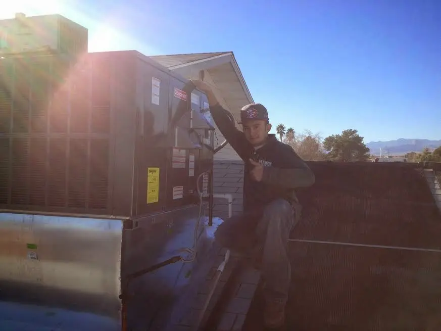 HVAC technician performing AC Tune-Up on a rooftop unit in Cambridge