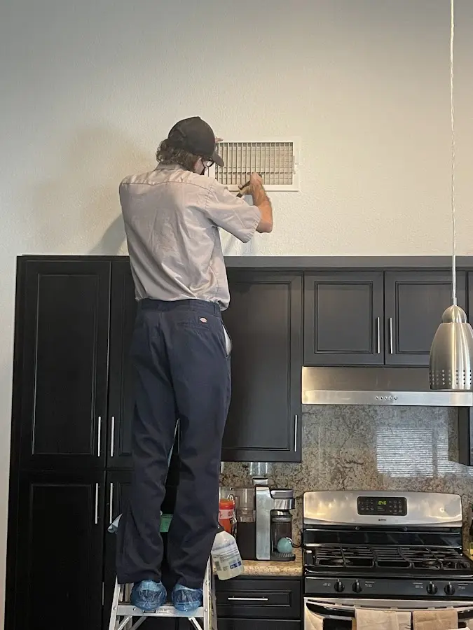 Technician inspecting an air vent during HVAC service in Cambridge
